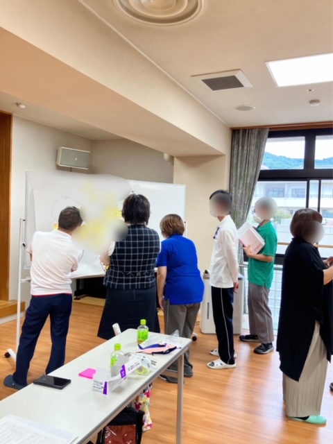 ホワイトボードを囲んで意見を出し合う対面研修の様子